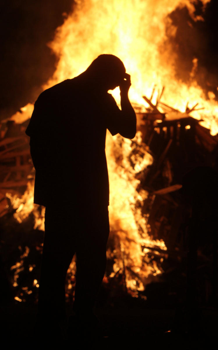 A military veteran pauses before a Memorial Day watchfire.