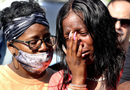 Julie Harwell, right, who was in the Tops supermarket in Buffalo, N.Y. when a gunman opened fire, killing ten people, is consoled during a prayer vigil across the street from the supermarket a day after the shooting May 15, 2022.