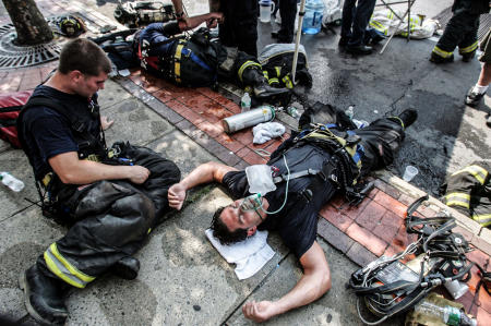 Firefighters suffer the effects of battling a fire during a summer heat wave.